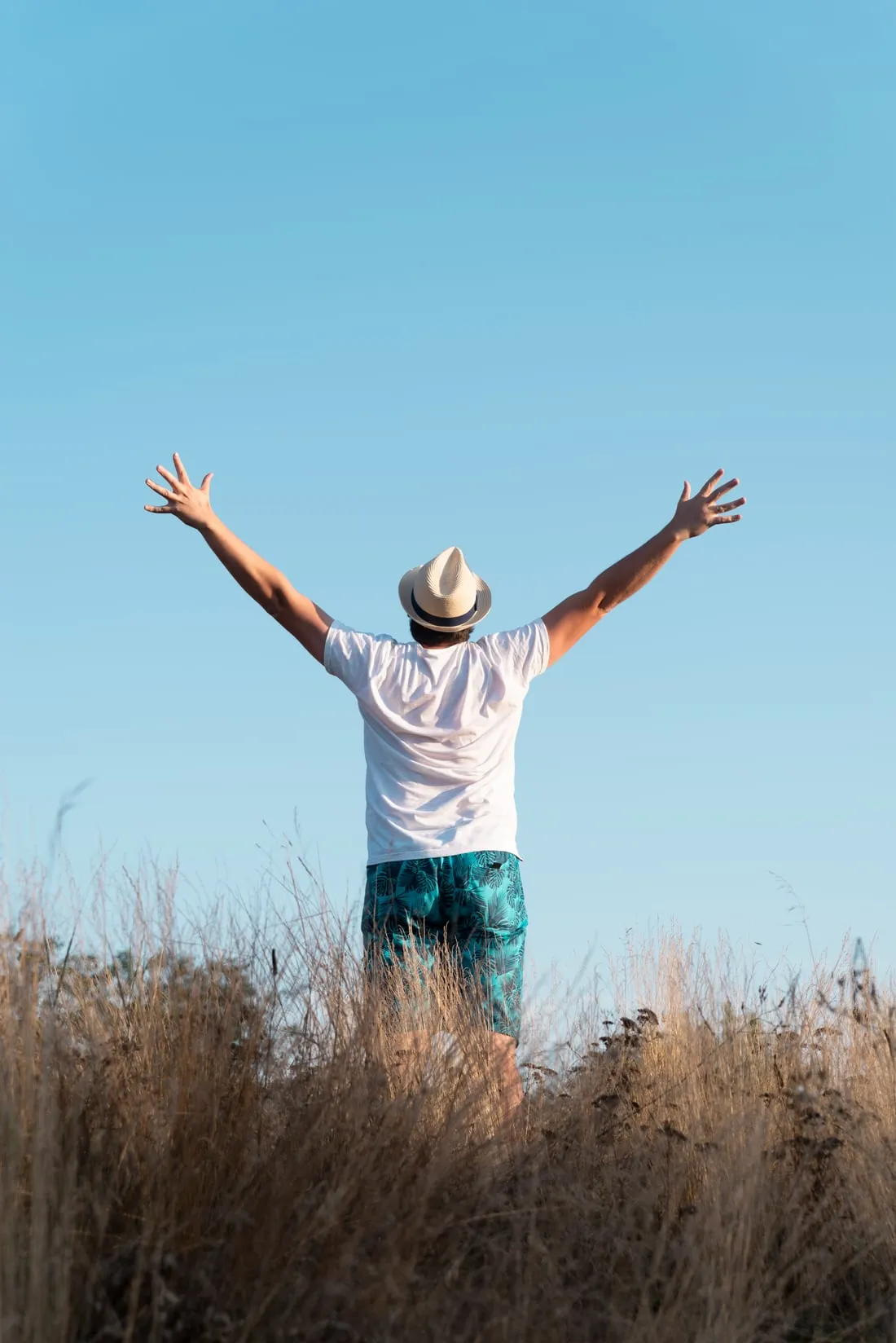 Un homme les bras ouverts sous un ciel bleu