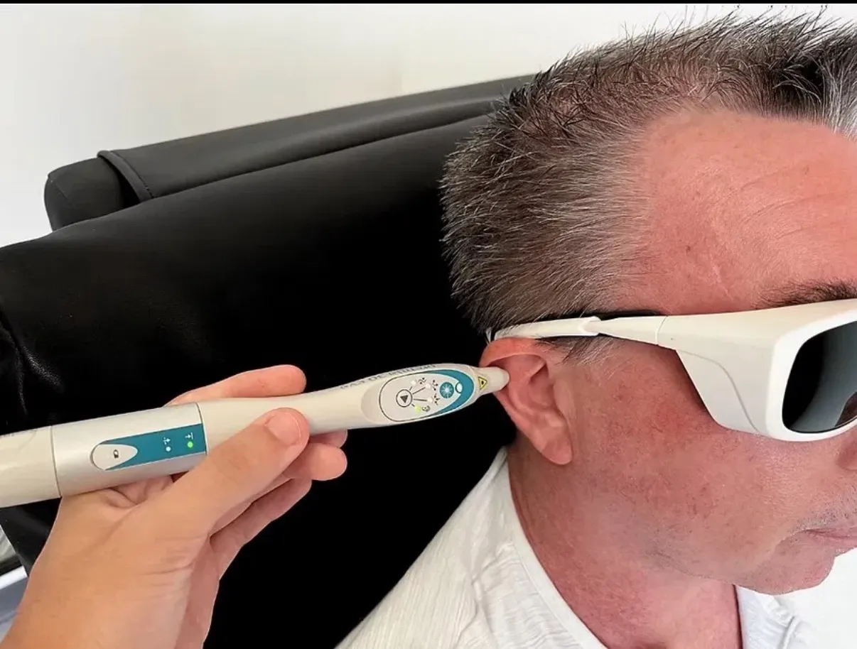 Séance de laser auriculaire au cabinet : le stylo laser posé sur l’oreille, lunettes de protection