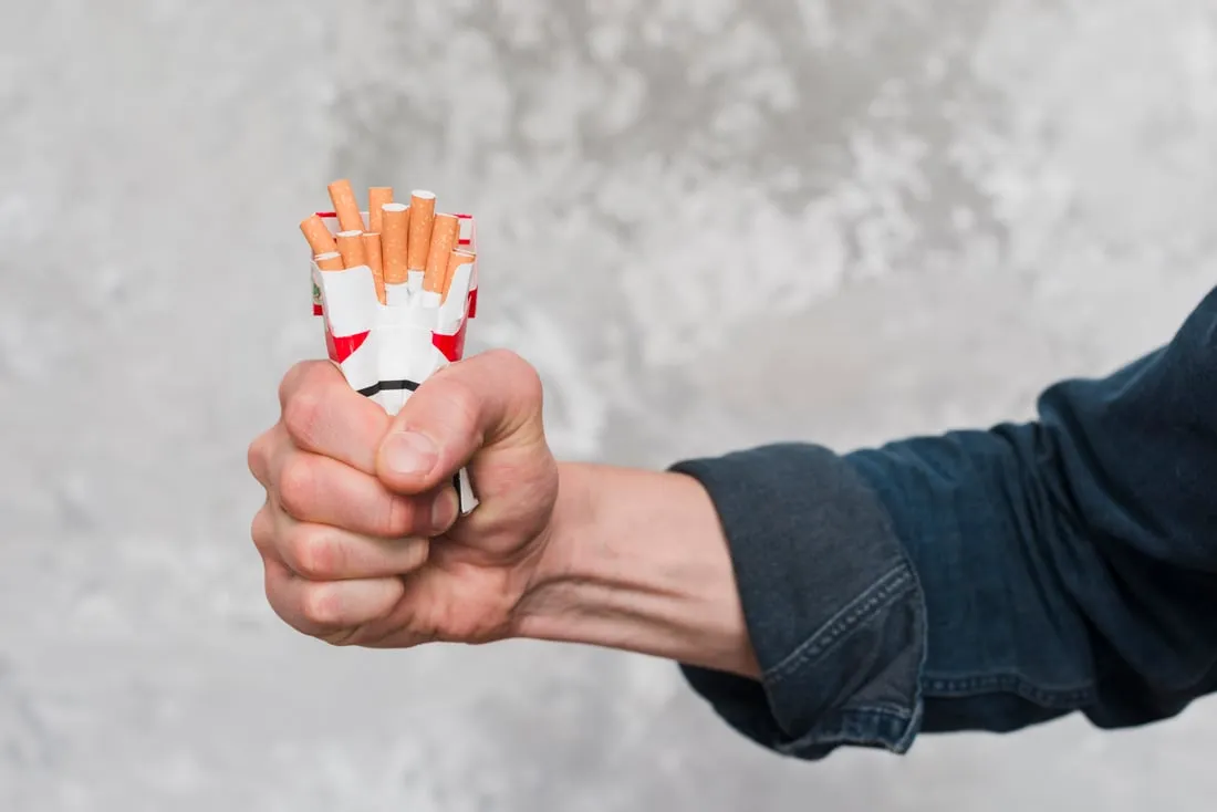 Une main écrasant des cigarettes